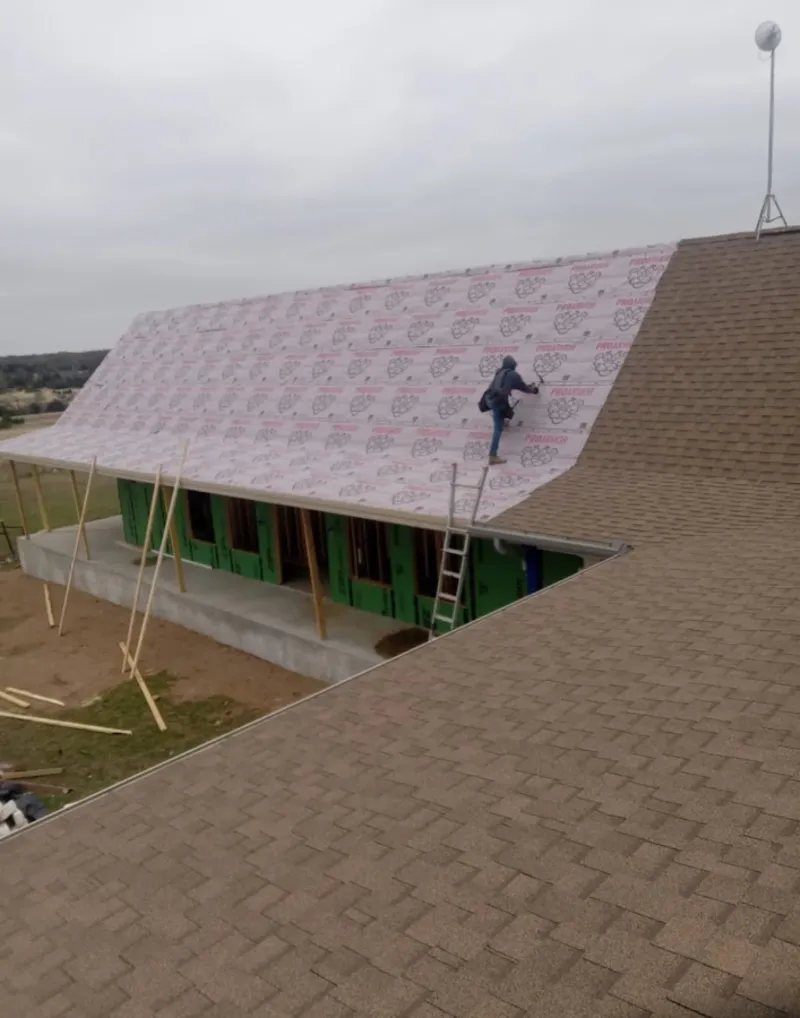 Worker preparing underlayment for a metal roof installation in Falmouth